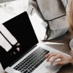 Side Hustle - Close-up Photography of Woman Sitting Beside Table While Using Macbook