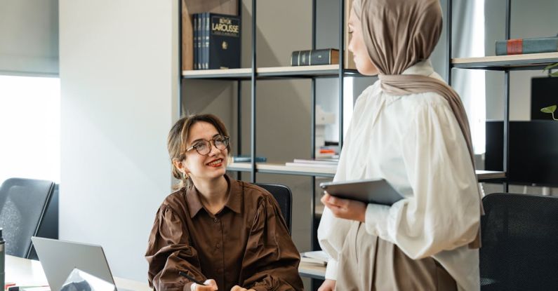 Business Continuity - Two women in hijab talking in an office