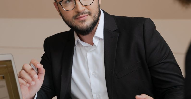 Business Negotiations - A Bearded Man in Black Suit Wearing Eyeglasses