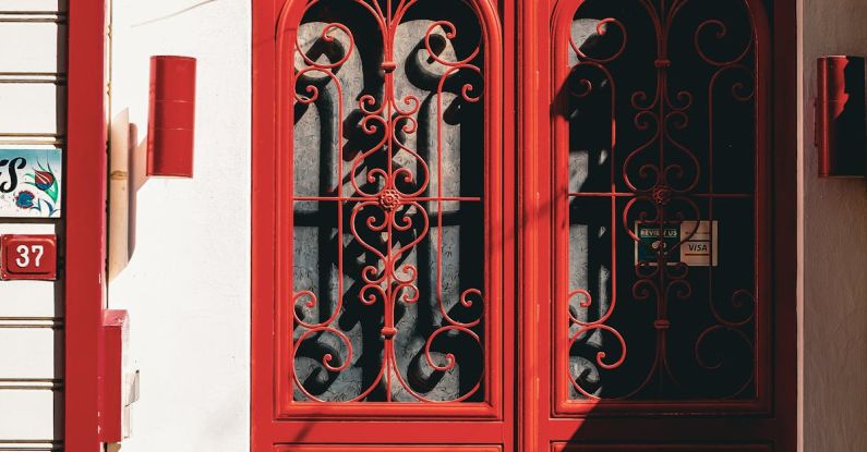 Entry Strategies - A red door with ornate ironwork on the side