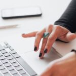 Serial Entrepreneur - Crop female using touchpad on laptop in office